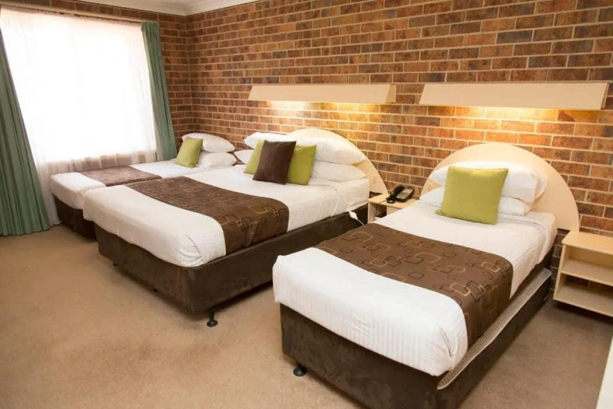 Family deluxe room with a queen and two single beds by a bright window